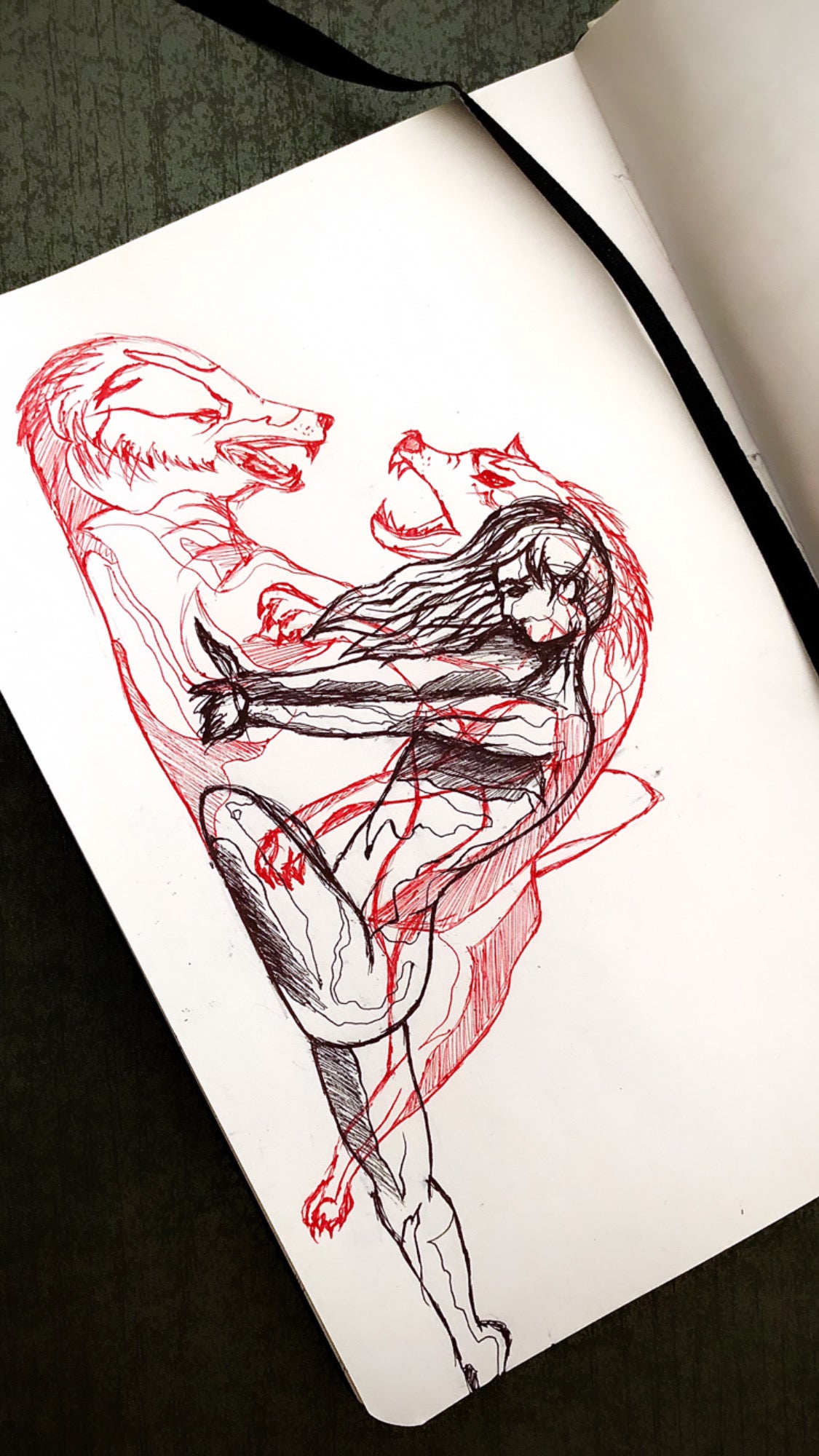 Sketchbook page with an expressive red and black drawing of a human figure intertwined with wolf-like forms